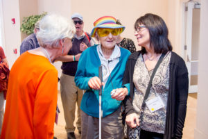 a group of people facing the camera Woman in the middle has a white cane