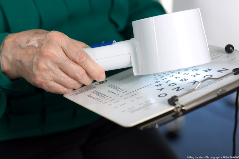 Woman's hand holding a magnifying device over text