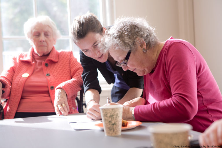 Two women at a table being assited by a volunteer