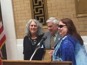 3 people standing at a podium at the state house