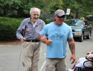 Steve Jordan guiding a man with a white cane