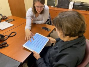 An accecss tech employee showing a participant how to use an iPad