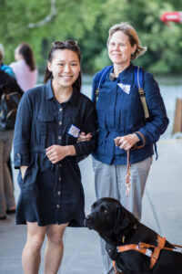 Image of a volunteer guiding a woman with a guide dog